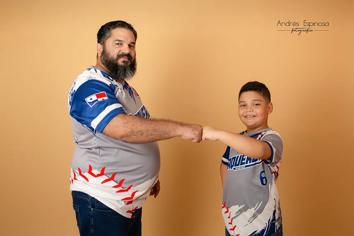 Foto en estudio Padre y niño beisbolista chocando los puños en fondo beige