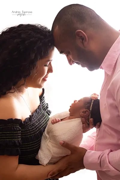Padres sosteniendo a su bebé recién nacido mientras se tocan las frentes con amor y ternura.